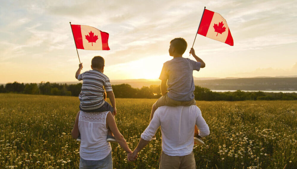 Adorable cute happy Caucasian boys holding Canadian flag on the father shoulder