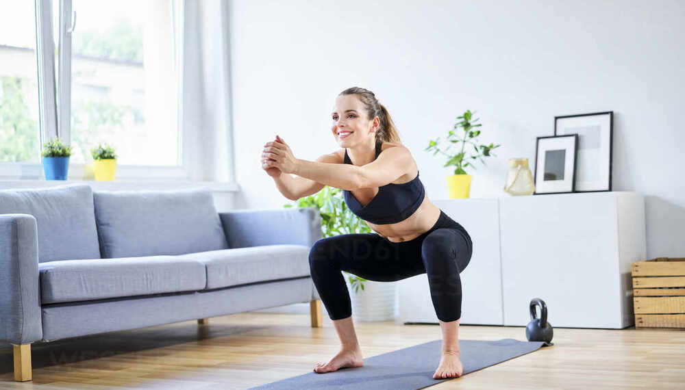 Smiling woman doing squats during home workout routine