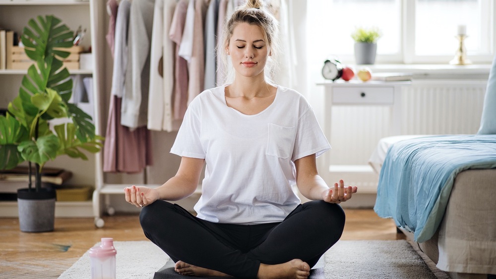 Young woman doing yoga exercise indoors at home, meditating.